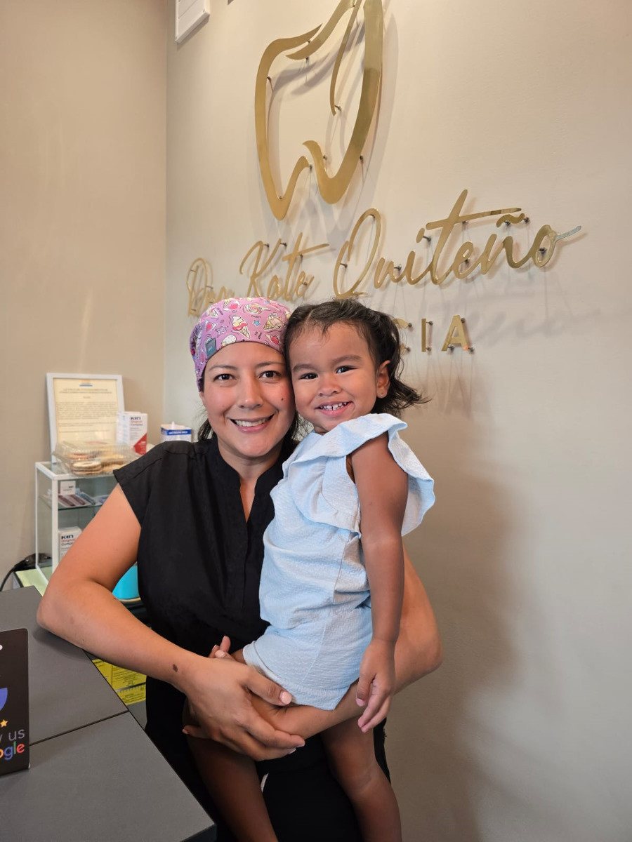 Dra. Kate Quiteño en su clínica junto al rótulo de la marca